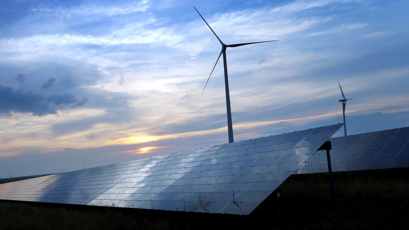 Solarzellen einer Solarkraftanlage vor Windrädern: Bis 2050 soll laut einer norwegischen Studie die Hälfte der Energie weltweit aus erneuerbaren Quellen stammen.