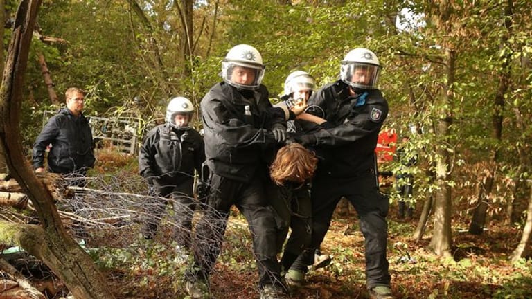 Im Hambacher Forst wird ein Aktivist von Polizisten abgeführt.