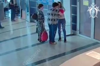 Video vom Flughafen: Eine 25-Jährige übergibt ihr Neugeborenes einer Lehrerin (Mitte). Eine ältere Frau hat sie zur Übergabe begleitet (links).