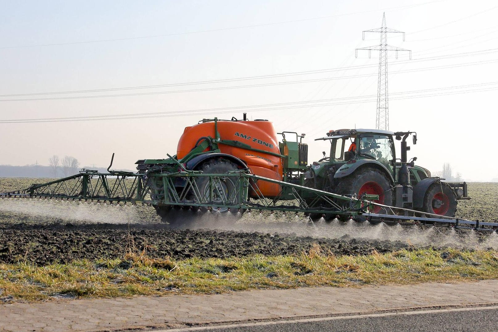 Ein Traktor zieht die Feldspritze über den Acker: Der Unkrautvernichter Glyphosat steht unter Verdacht Bienen zu schädigen.