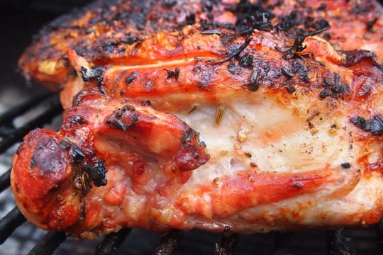 Etwa eine Stunde braucht die Spanferkelkeule auf dem Grill: Für die passende Würze sorgt eine Paste aus Knoblauch, Fenchel, Rosmarin und Thymian.