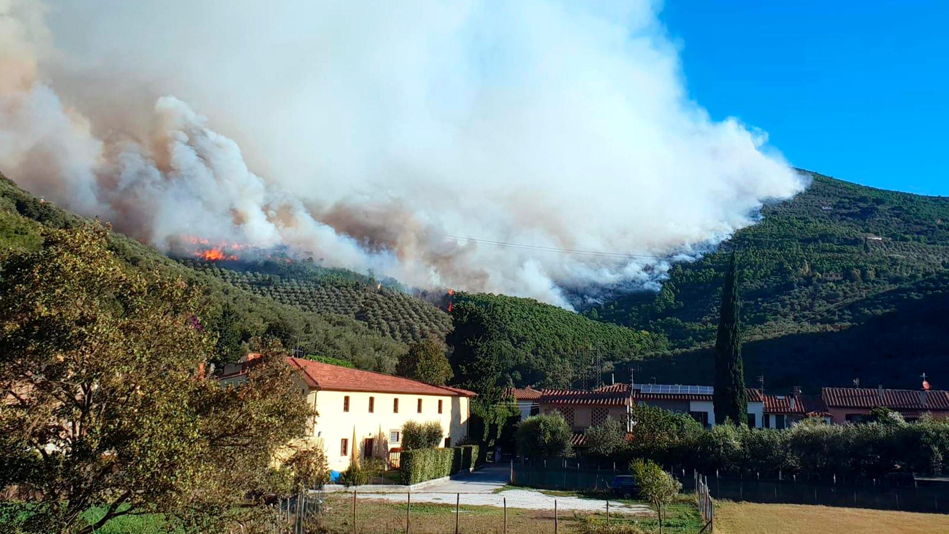 Rauch steigt über dem Dorf Calci auf: Ein Großbrand auf dem Monte Serra hat die Evakuierung von Hunderten von Menschen aus ihren Dörfern in der Toskana erzwungen. Rauch steigt über dem Dorf Calci auf: Ein Großbrand auf dem Monte Serra hat die Evakuierung von Hunderten von Menschen aus ihren Dörfern in der Toskana erzwungen.