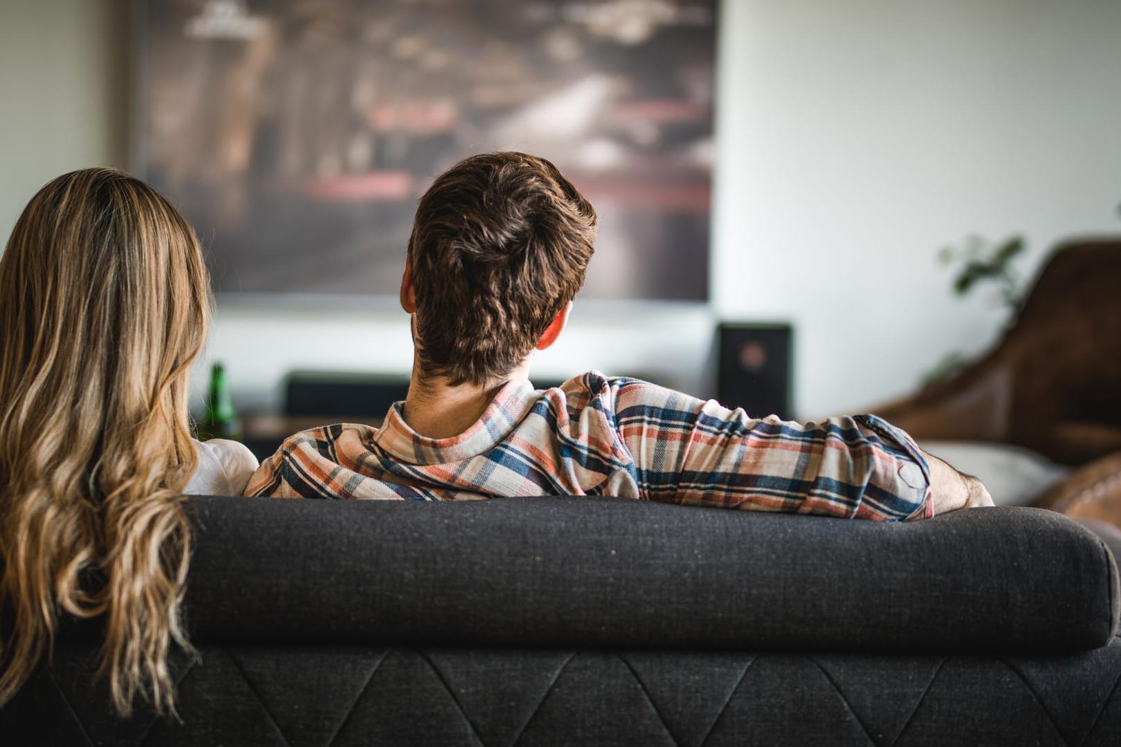 Pärchen beim Fernseh-Gucken (Symbolbild): Wer sich unsicher ist, welche TV-Größe für den eigenen Bedarf passend ist, kann sich mit einem Pappen-Test behelfen