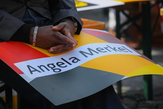 Mann mit dunkler Hautfarbe und Merkel-Plakat: SPD und Grüne verlieren einer neuen Studie zufolge bei Zuwandern an Beliebtheit.