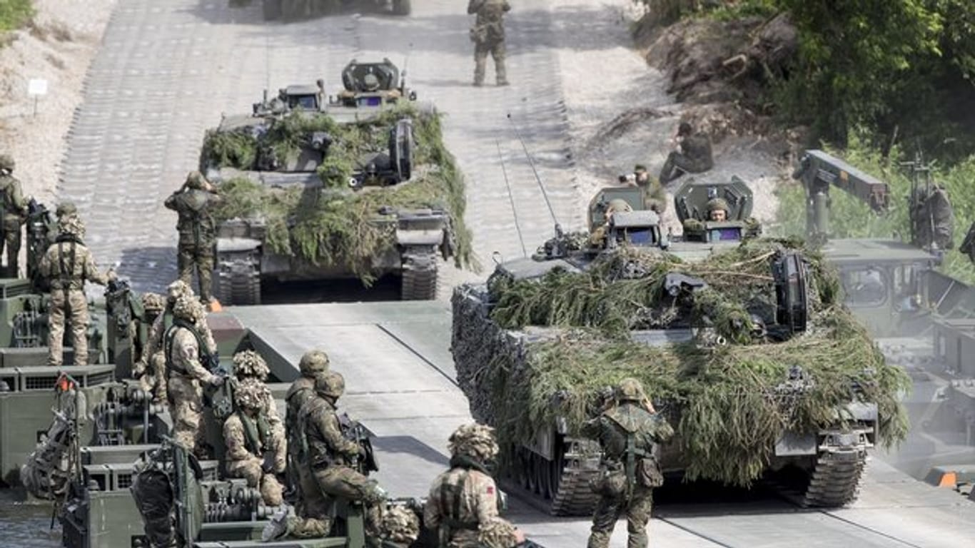 Bundeswehrsoldaten überqueren während eines Nato-Manövers in Litauen auf einer Pontonbrücke einen Fluß.