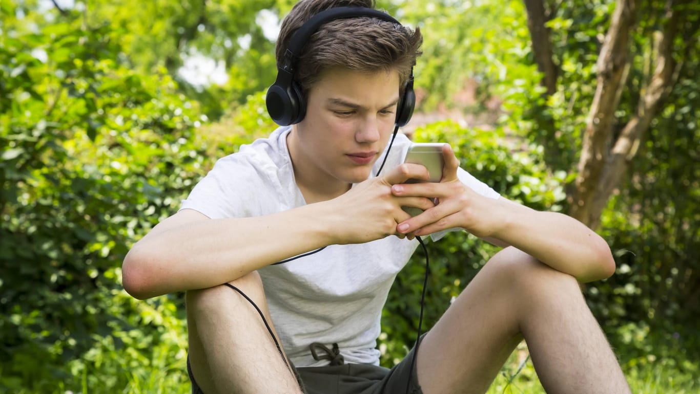 Ein Junge sitzt vor seinem Smartphone: Die in der Studie untersuchten Kinder verbrachten im Schnitt 3,6 Stunden vor Bildschirmen.