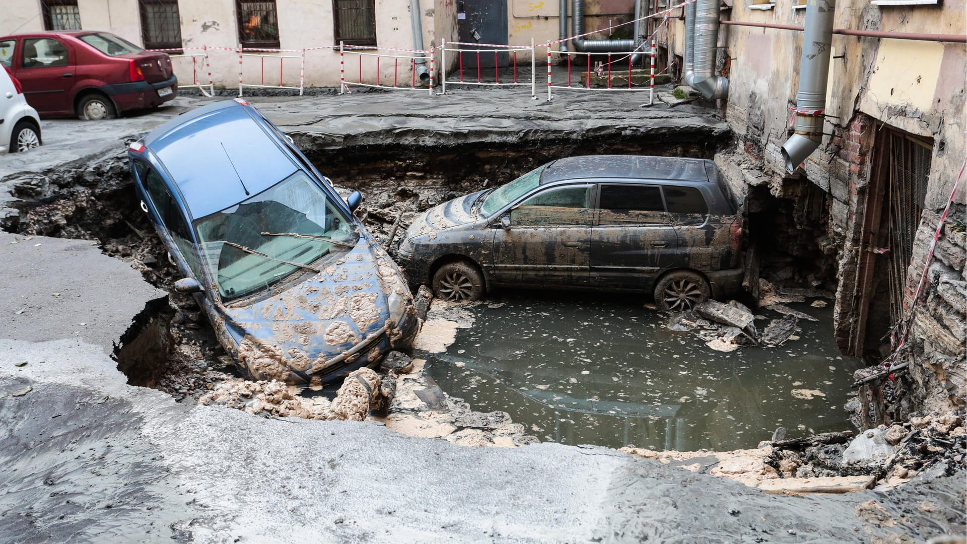 Fahrzeuge auf einer eingebrochenen Straße: Nach einem Leitungsbruch drang kochend heißes Wasser in ein nahe gelegenes Keller-Café.