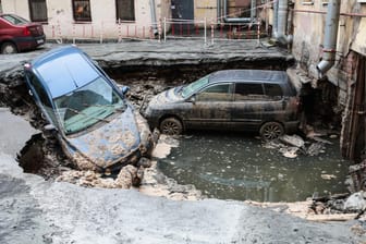 Fahrzeuge auf einer eingebrochenen Straße: Nach einem Leitungsbruch drang kochend heißes Wasser in ein nahe gelegenes Keller-Café.