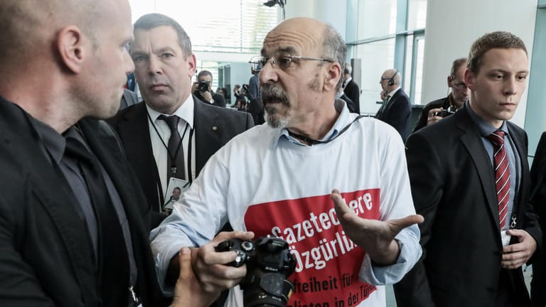 Adil Yigit: Der Journalist trug in der Pressekonferenz von Merkel und Erdogan ein T-Shirt mit der Aufschrift "Pressefreiheit für Journalisten in der Türkei" und auf Türkisch "Freiheit für die Journalisten".