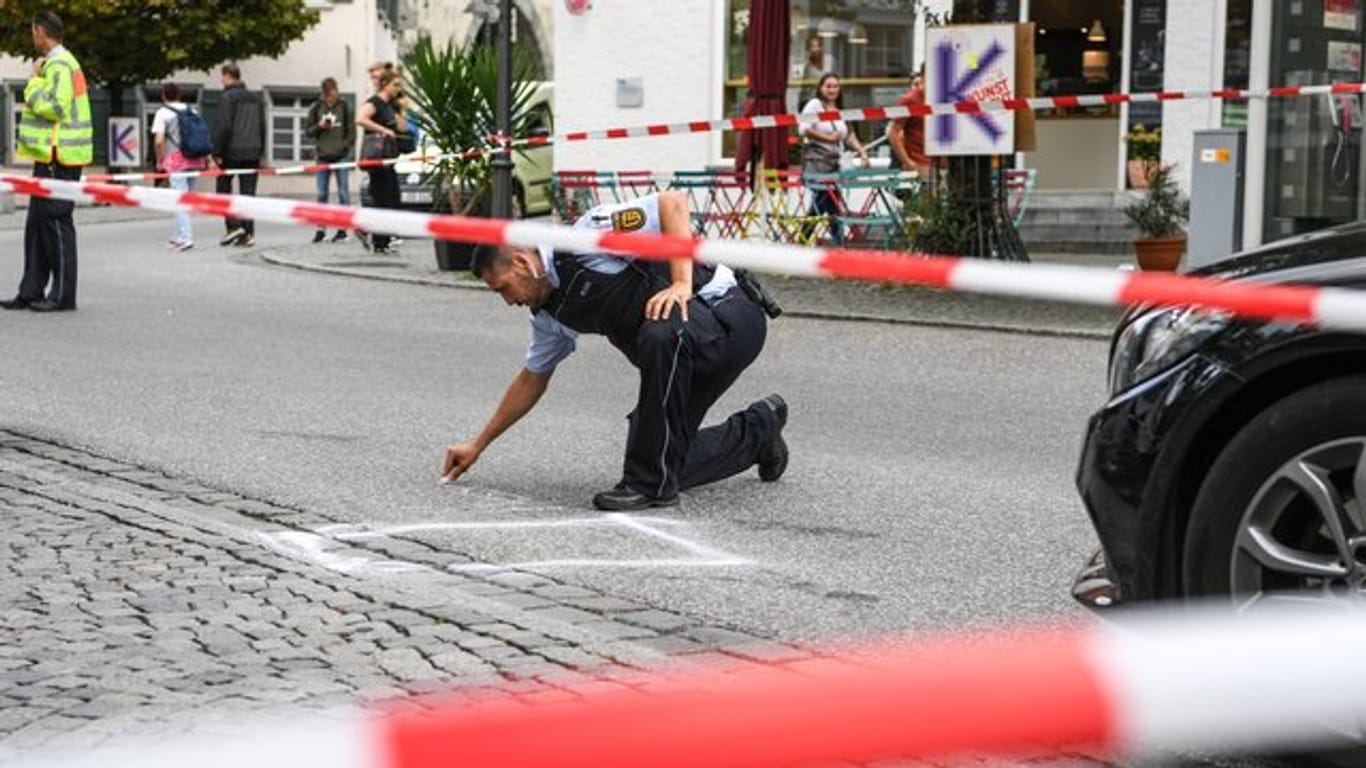 Ein Polizist markiert im abgesperrten Tatort auf dem Marienplatz den Bereich, wo das Tatmesser lag.