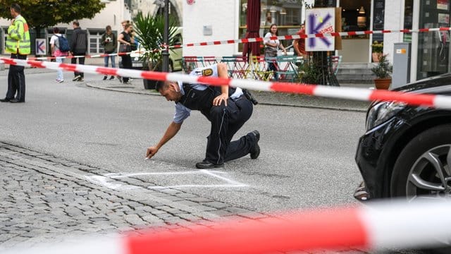 Ein Polizist markiert im abgesperrten Tatort auf dem Marienplatz den Bereich, wo das Tatmesser lag.