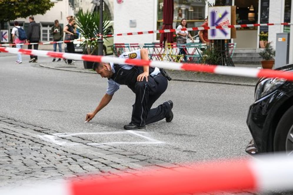 Ein Polizist markiert im abgesperrten Tatort auf dem Marienplatz den Bereich, wo das Tatmesser lag.