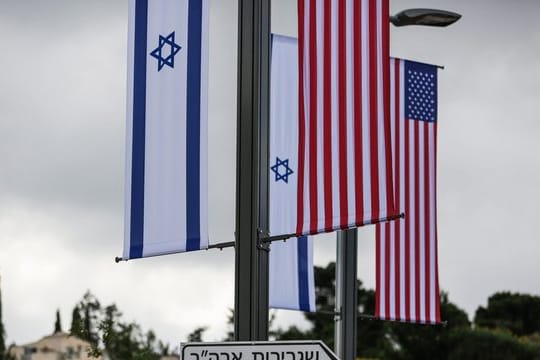 Eine Israelische und US-Flagge sind über einem Schild angebracht, das den Weg zur Botschaft der USA weist (Archiv).