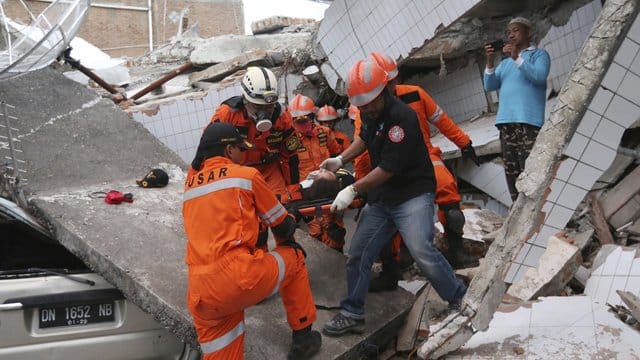 Rettungskräfte tragen einen Verletzten aus den Trümmern eines Restaurants, das durch das Erdbeben und den darauf folgenden Tsunami zerstört wurde. Rettungskräfte tragen einen Verletzten aus den Trümmern eines Restaurants, das durch das Erdbeben und den darauf folgenden Tsunami zerstört wurde.