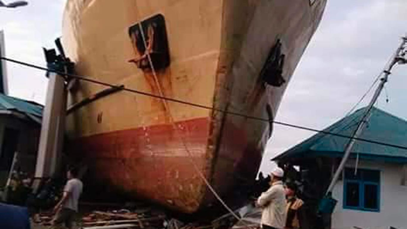 Palu, Indonesien: Anwohner stehen vor einem Schiff, das der Tsunami zwischen ihre Häuser gespült hat.
