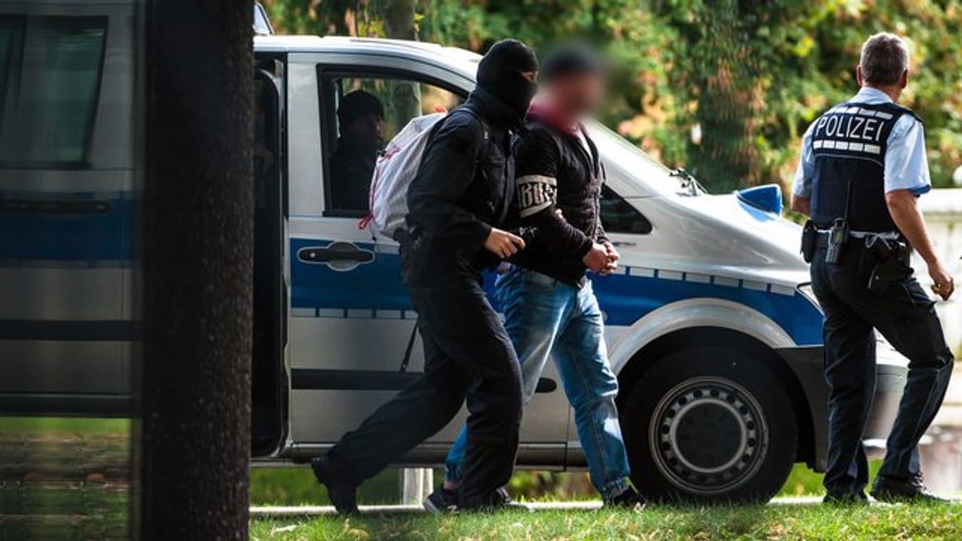 Einer der Verdächtigen wird vor dem Bundesgerichtshof in Karlsruhe von Polizisten abgeführt.