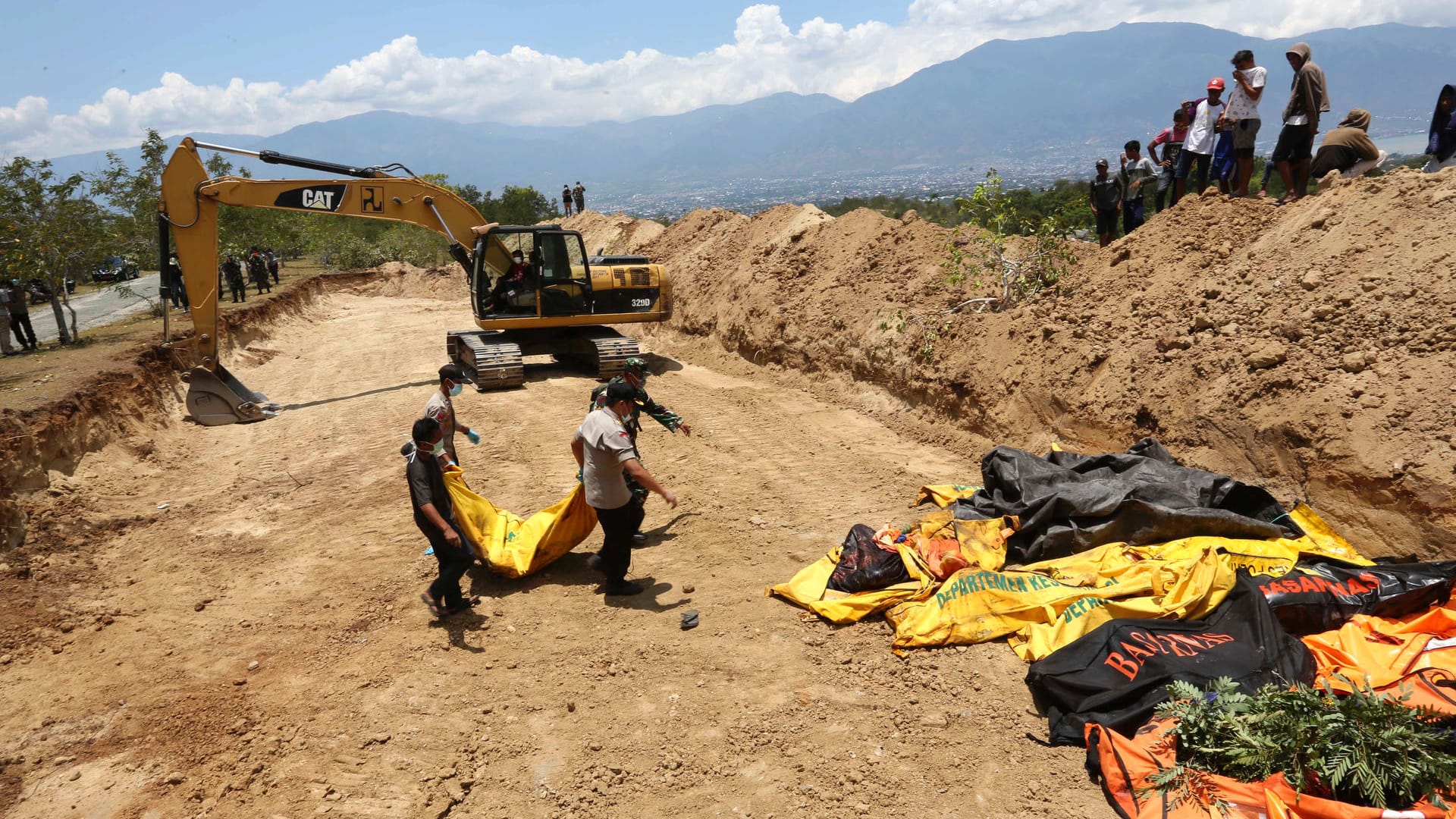 Massenbestattung: Die indonesische Polizei bringt die Leiche eines Tsunami-Opfers zu weiteren Leichensäcken.