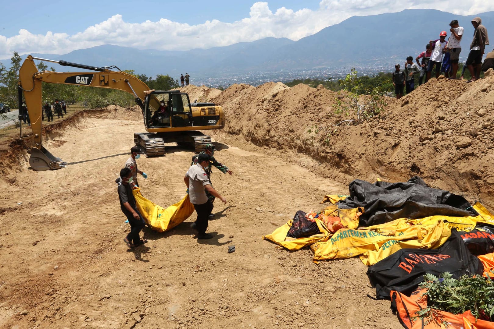 Massenbestattung: Die indonesische Polizei bringt die Leiche eines Tsunami-Opfers zu weiteren Leichensäcken.