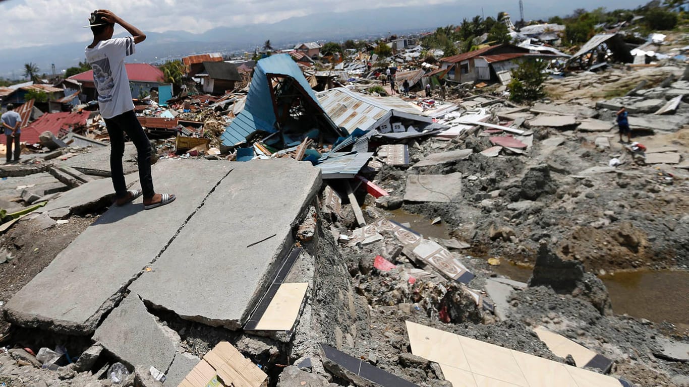 Indonesien, Palu: Zwei Männer überblicken die Schäden nach den Erdbeben und dem Tsunami. Nach einer offiziellen Zwischenbilanz kamen bei der Serie von Beben und dem folgenden Tsunami an der Westküste Sulawesis mehr als 1200 Menschen ums Leben.