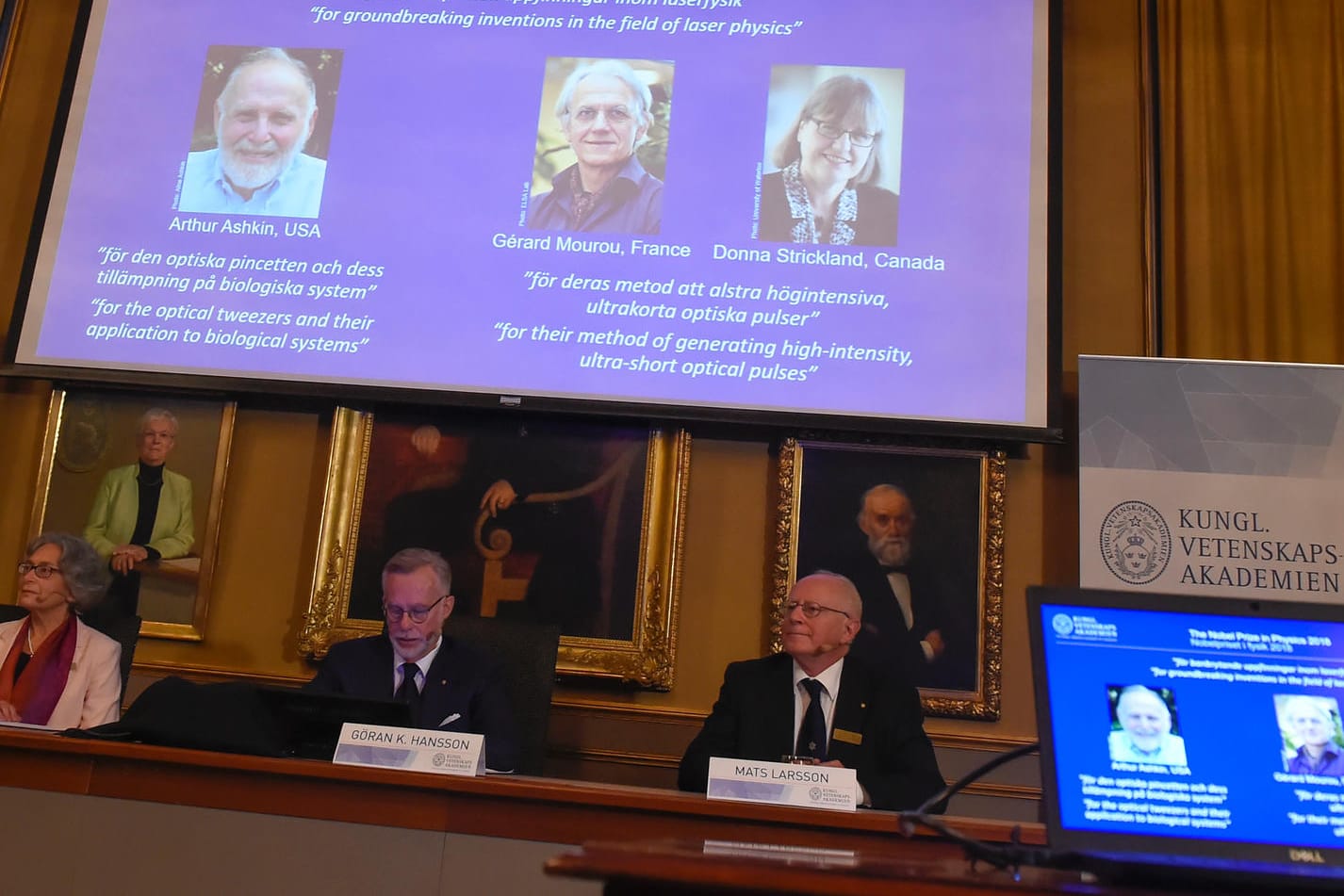 Schweden, Stockholm: Die Nobelpreisträger für Physik 2018, Arthur Ashkin aus den USA (von links nach rechts), Gerard Mourou aus Frankreich und Donna Strickland aus Kanada, sind auf einem Bildschirm während der Verkündung in der Königlich Schwedischen Akademie der Wissenschaften zu sehen.