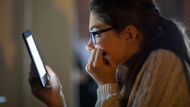 Eine Frau liest auf einem digitalen Lesegerät ein E-Book.