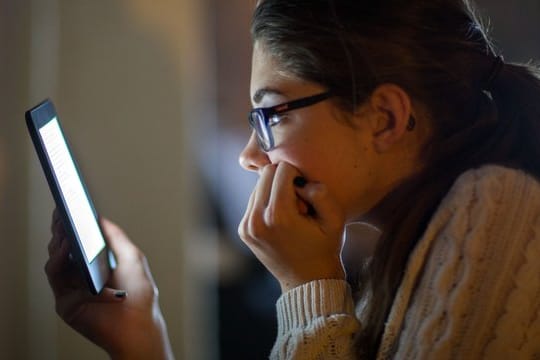 Eine Frau liest auf einem digitalen Lesegerät ein E-Book.