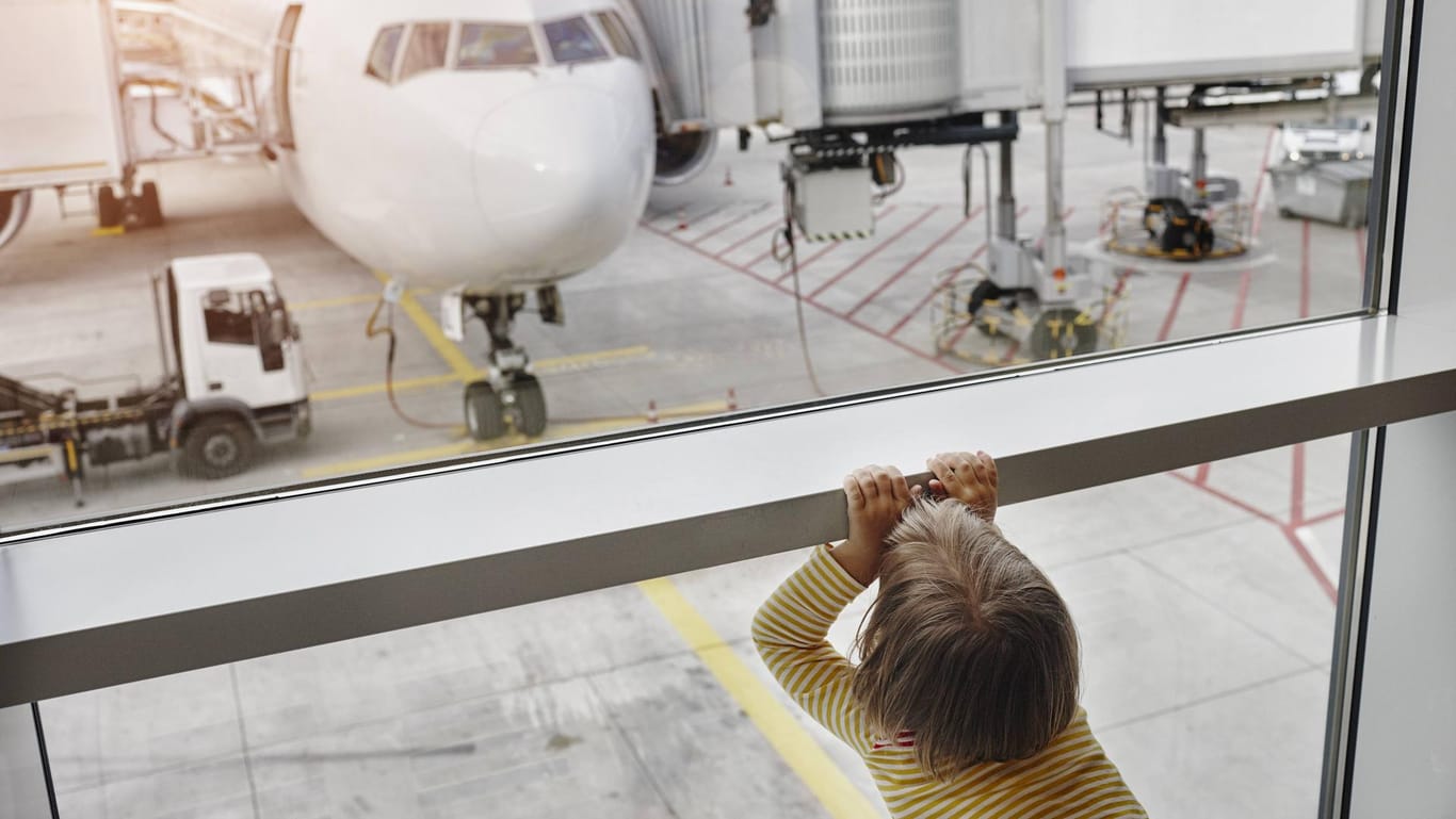 Ein kleines Mädchen schaut durch ein Fenster auf ein Flugzeug: In Stuttgart vergaßen Eltern ihre fünfjährige Tochter am Flughafen.