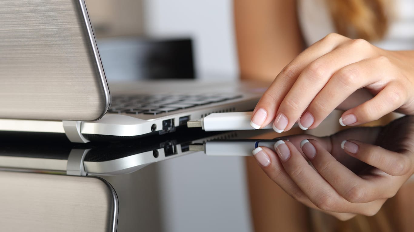 Eine Frau steckt einen USB-Stick in ihren Laptop: Auf der Handelsplattform werden viele gefälschte Speichermedien angeboten.