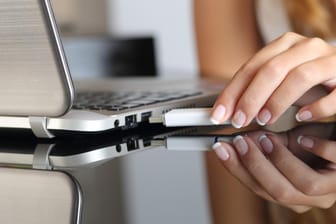 Eine Frau steckt einen USB-Stick in ihren Laptop: Auf der Handelsplattform werden viele gefälschte Speichermedien angeboten.