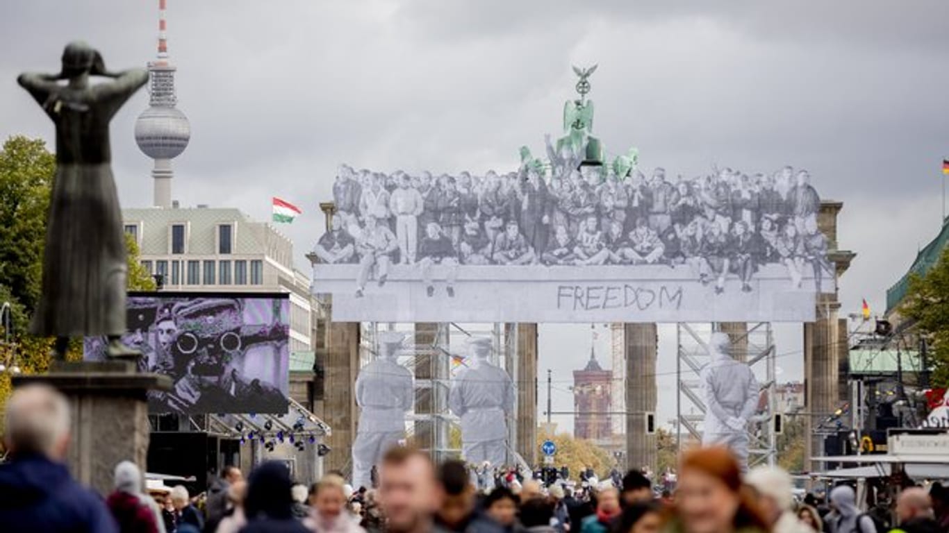 Besucher des Bürgerfests tummeln sich vor dem mit einer Installation des Street Art-Künstlers JR versehenen Brandenburger Tor.