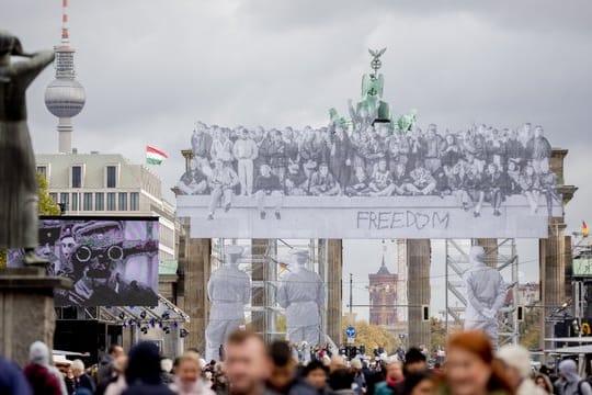 Besucher des Bürgerfests tummeln sich vor dem mit einer Installation des Street Art-Künstlers JR versehenen Brandenburger Tor.