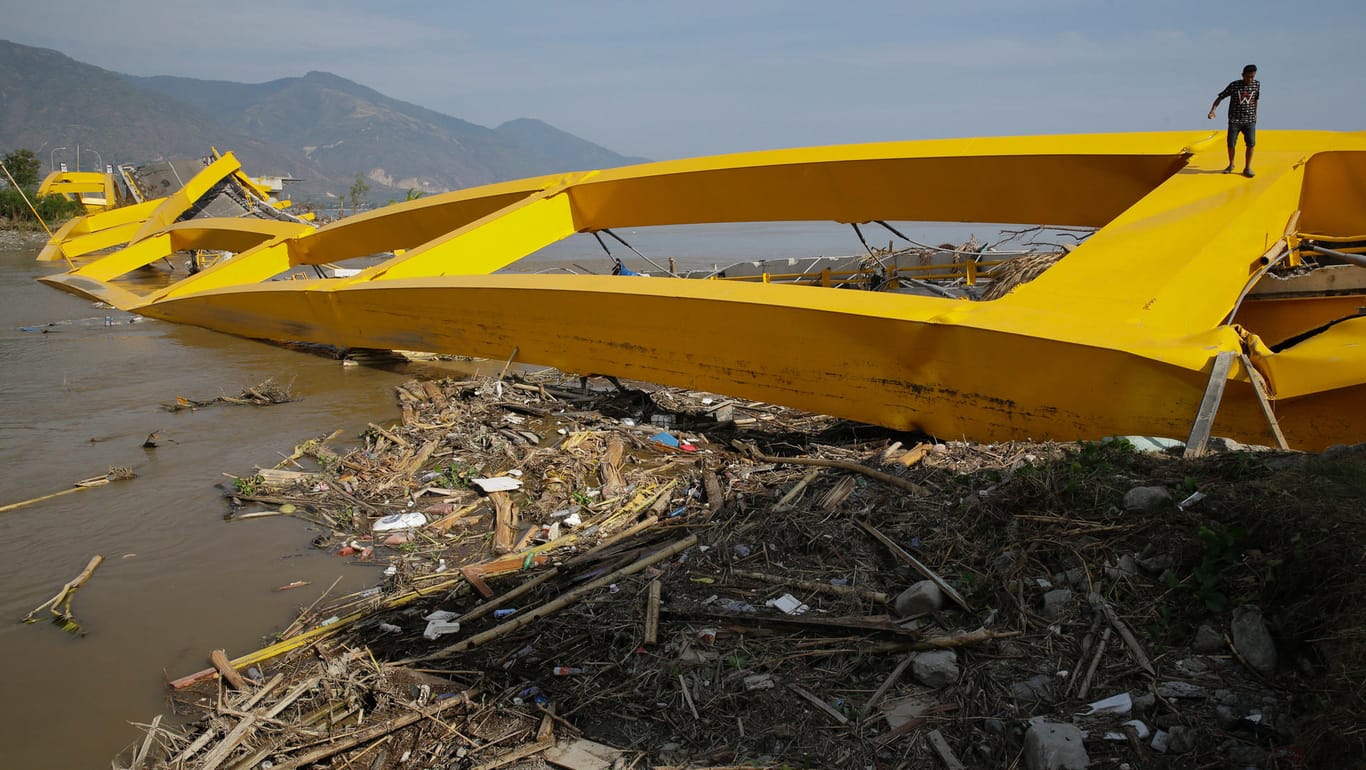 Ein Mann auf einer vom Tsunami zerstörten Brücke in Palu: Inzwischen haben die ersten Hilfsgüter die stark betroffene Großstadt erreicht.