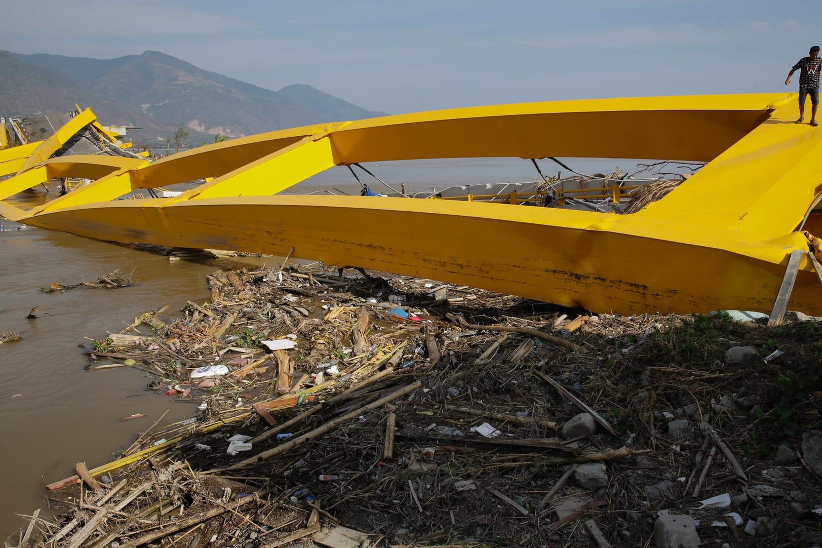 Ein Mann auf einer vom Tsunami zerstörten Brücke in Palu: Inzwischen haben die ersten Hilfsgüter die stark betroffene Großstadt erreicht.