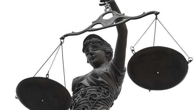 Eine Statue der Justitia mit einer Waage in ihrer Hand.