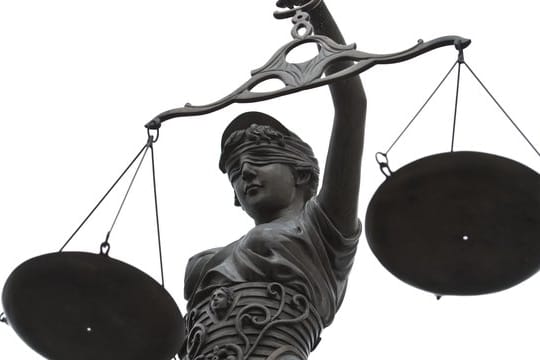 Eine Statue der Justitia mit einer Waage in ihrer Hand.