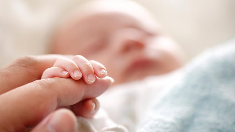 Baby hält die Hand seiner Mutter: Zuwendung, Berührung, Blickkontakt: Das lässt eine gute Bindung zwischen Eltern und Kind wachsen.