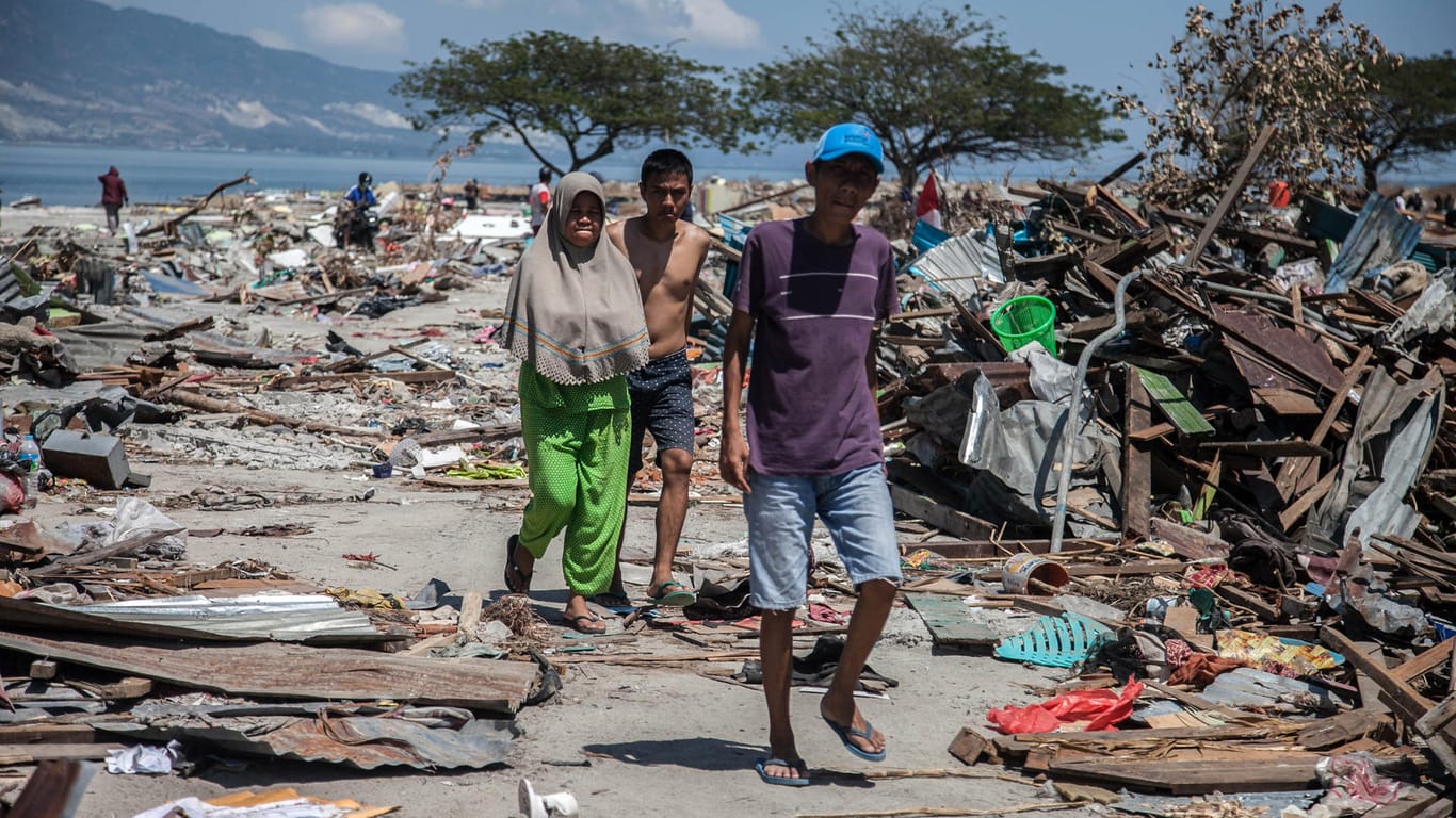 Dorfbewohner wandern durch die Trümmer: Auch eine Woche nach den Erdbeben und dem Tsunami in Indonesien zeichnet sich erst allmählich das ganze Ausmaß der Schäden ab.