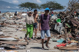 Dorfbewohner wandern durch die Trümmer: Auch eine Woche nach den Erdbeben und dem Tsunami in Indonesien zeichnet sich erst allmählich das ganze Ausmaß der Schäden ab.