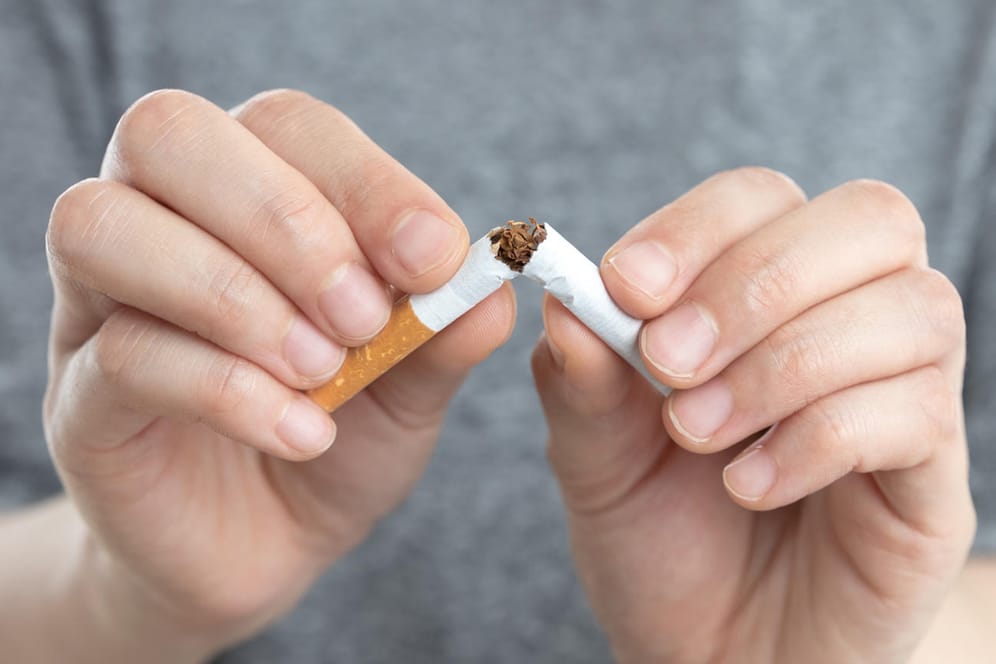 Ein Mann zerbricht eine Zigarette: Warten Sie nicht bis zum Jahresanfang, wenn Sie mit dem Rauchen aufhören wollen.