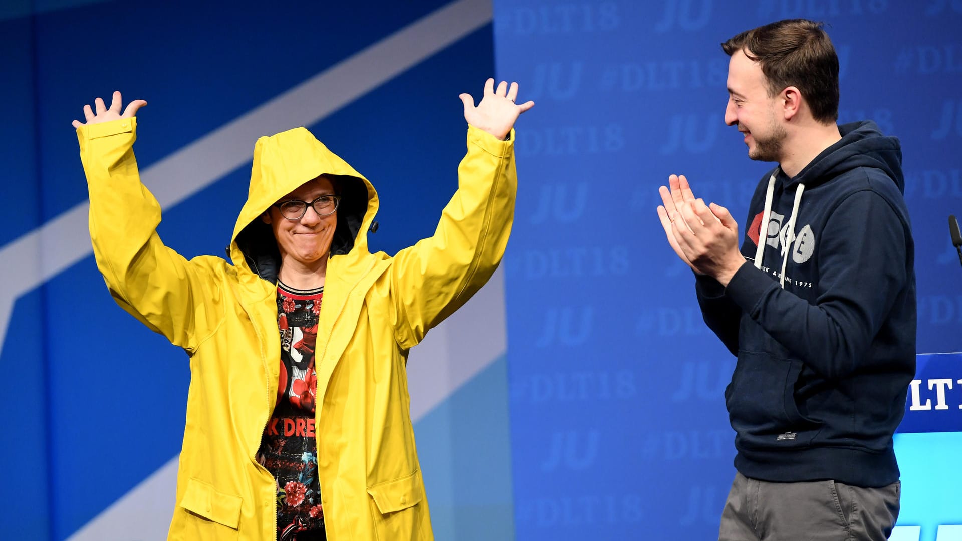 Annegret Kramp-Karrenbauer lässt sich von der Jungen Union und deren Chef Paul Ziemiak feiern – und probiert die geschenkte Regenjacke direkt aus.