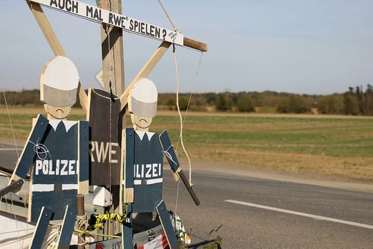 Hampelmänner von Braunkohlegegnern hängen am Hambacher Forst am Straßenrand.