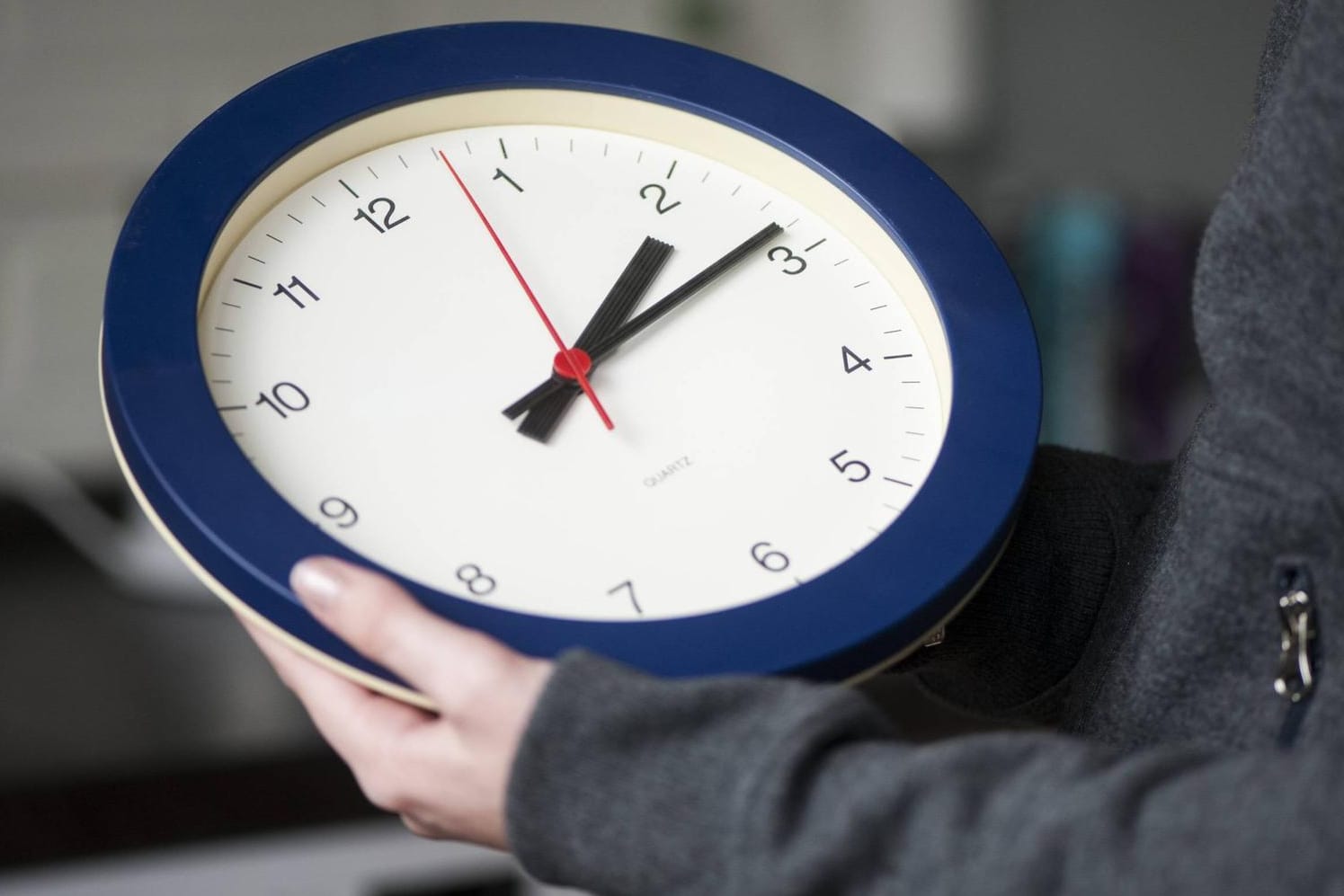 Eine Frau hält eine Wanduhr (Symbolbild): In den EU-Staaten formiert sich Widerstand gegen die Pläne zur Abschaffung der Zeitumstellung.