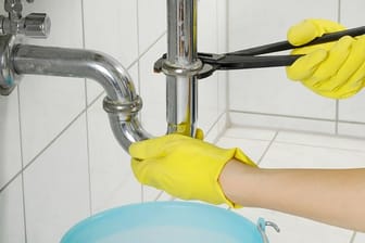 Bei hartnäckigen Verstopfungen lösen Heimwerker den Siphon des Waschbeckens und reinigen die Rohre mit einer Bürste.