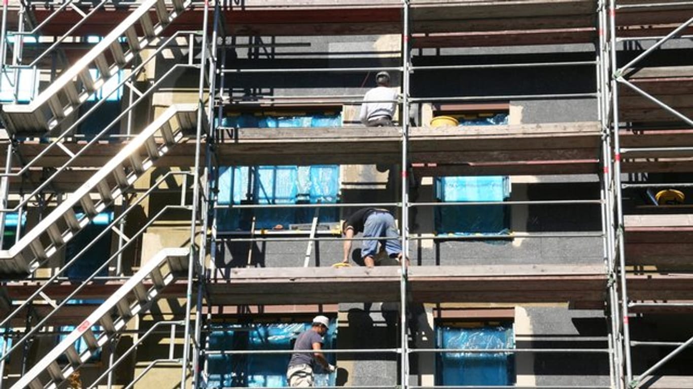 Arbeiter stehen beim Bau von Eigentumswohnungen auf einem Gerüst in Berlin.