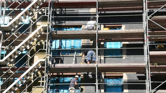 Arbeiter stehen beim Bau von Eigentumswohnungen auf einem Gerüst in Berlin. Arbeiter stehen beim Bau von Eigentumswohnungen auf einem Gerüst in Berlin.