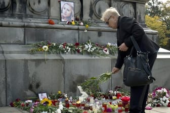Eine Frau legt Blumen vor einem Bild der ermordeten Journalistin Wiktorija Marinowa am Freiheitsdenkmal in Russe nieder.
