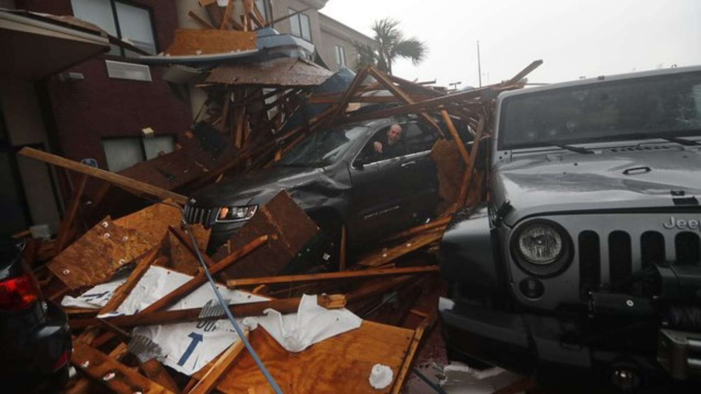 Ein Sturmjäger klettert während das Auge von Hurrikan "Michael" vorbei zieht in sein verschüttetes Auto um Ausrüstung zu bergen.