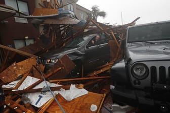 Ein Sturmjäger klettert während das Auge von Hurrikan "Michael" vorbei zieht in sein verschüttetes Auto um Ausrüstung zu bergen.