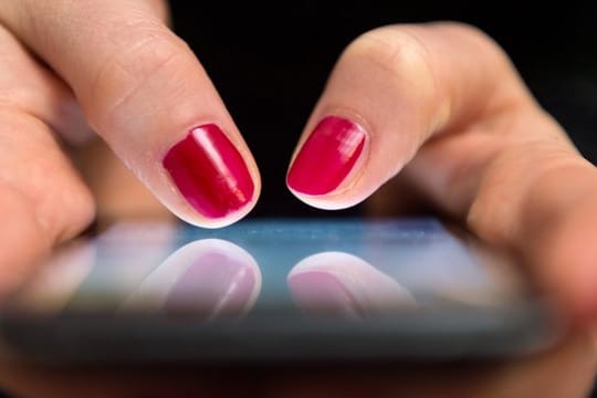 Eine Frau tippt auf einem Smartphone.