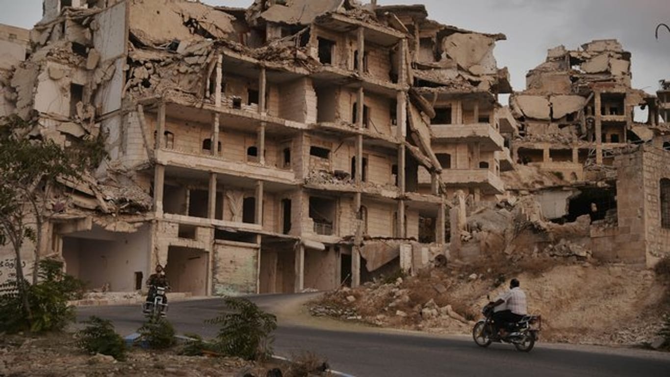 Motorräder fahren an Gebäuden vorbei, die im Zuge der Kämpfe in der Provinz Idlib zerstört wurden.